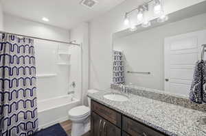 Full bathroom with toilet, shower / bath combo with shower curtain, vanity, and hardwood / wood-style flooring