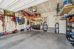 Garage featuring a garage door opener, white fridge, and a workshop area