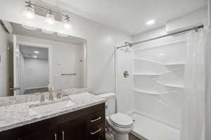 Bathroom with vanity, toilet, and curtained shower