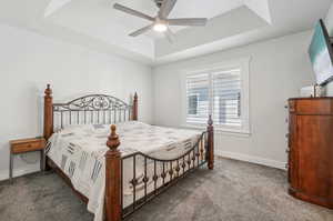 Carpeted bedroom with ceiling fan and a raised ceiling