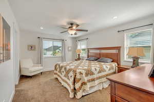 Bedroom with multiple windows, light carpet, and ceiling fan