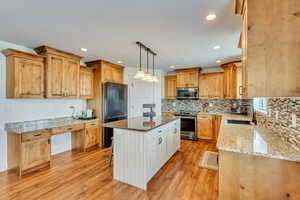 Kitchen featuring a center island, light hardwood / wood-style floors, appliances with stainless steel finishes, a kitchen breakfast bar, and sink