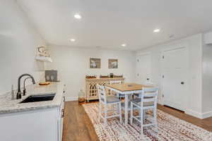 Kitchen with sink, white cabinetry, light stone counters, and dark hardwood / wood-style floors