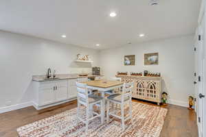 Kitchen featuring sink, dark hardwood / wood-style floors, light stone counters, and white cabinets