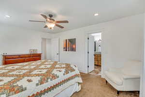 Bedroom featuring light tile patterned flooring, connected bathroom, and ceiling fan