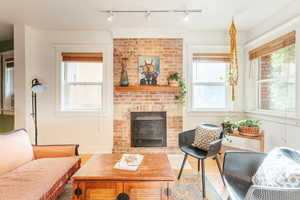 Living room with rail lighting, hardwood  floors, and a brick fireplace