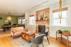 Living room featuring hardwood flooring, rail lighting, and a brick fireplace