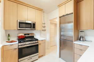 Kitchen featuring stainless steel appliances and light brown modern cabinetry