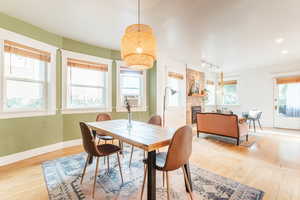 Dining area with light hardwood flooring, rail lighting, and a fireplace