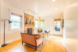 Living room featuring hardwood flooring, a brick fireplace, and rail lighting