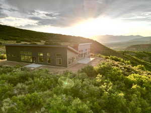 Back house at dusk with a mountain view and a patio area