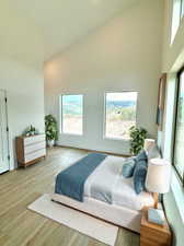 Bedroom with light hardwood / wood-style flooring, multiple windows, and high vaulted ceiling