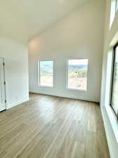 Unfurnished bedroom with high vaulted ceiling and light wood-type flooring