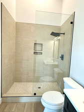 Bathroom with vanity, tiled shower, hardwood / wood-style flooring, and toilet