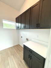 Laundry area featuring washer hookup, electric dryer hookup, light hardwood / wood-style flooring, and cabinets