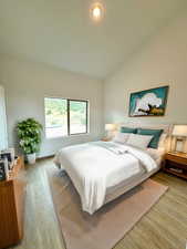 Bedroom with hardwood / wood-style flooring and vaulted ceiling