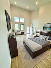 Bedroom with light hardwood / wood-style floors and a towering ceiling