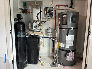 Utility room featuring strapped water heater