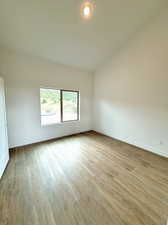 Unfurnished bedroom with vaulted ceiling and light hardwood / wood-style floors