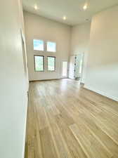 Unfurnished bedroom with light wood-type flooring and a towering ceiling