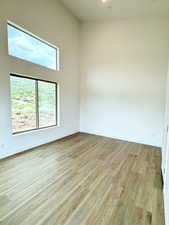 Empty room featuring light wood-type flooring and a towering ceiling