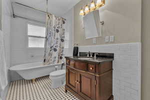 Full bathroom featuring tile walls, vanity, tile patterned flooring, and toilet