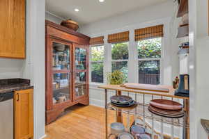 Kitchen with stainless steel dishwasher, dark stone counters, and light wood-type flooring