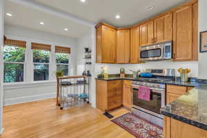 Kitchen featuring appliances with stainless steel finishes, light hardwood / wood-style flooring, and dark stone counters