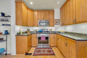 Kitchen with dark stone counters, light wood-type flooring, and stainless steel appliances