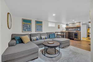 Living room with wine cooler, sink, and wood-type flooring