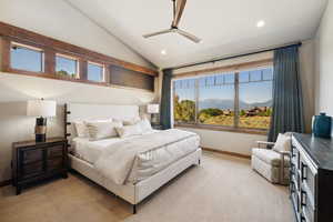 Bedroom featuring ceiling fan, vaulted ceiling, multiple windows, and light colored carpet