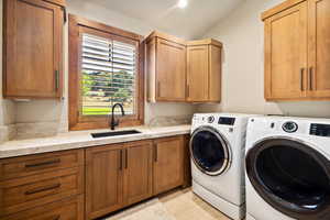 Laundry room featuring washer and dryer, sink, light tile patterned floors, and cabinets