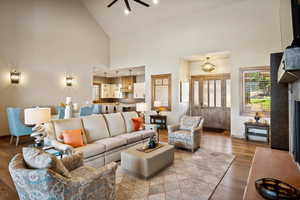 Living room with ceiling fan, high vaulted ceiling, and light hardwood / wood-style floors