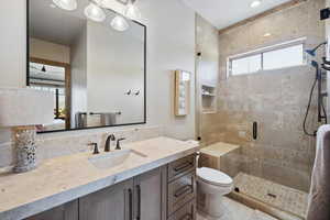 Bathroom with vanity, toilet, walk in shower, and tile patterned flooring