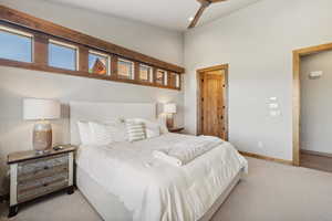 Carpeted bedroom with ceiling fan and vaulted ceiling