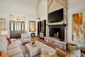 Living room with wood-type flooring, a fireplace, and high vaulted ceiling