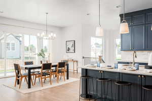 Kitchen featuring decorative backsplash, a breakfast bar, an inviting chandelier, and light hardwood / wood-style floors