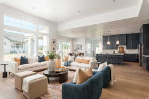 Living room with light wood-type flooring, a chandelier, and a healthy amount of sunlight