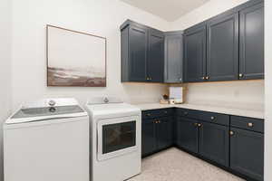 Laundry room with cabinets, light tile patterned floors, and washer and dryer