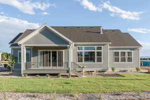 Rear view of property featuring covered porch and a yard