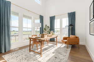 Home office with hardwood / wood-style floors, a wealth of natural light, and a high ceiling