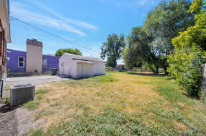 View of yard with a shed and central AC unit