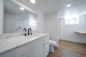 Full bathroom featuring a textured ceiling, toilet, wood-type flooring, shower / bathtub combination, and vanity