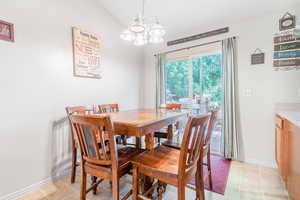 Dining area featuring an inviting chandelier, light tile patterned flooring, and lofted ceiling