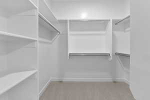 Walk in closet featuring light colored carpet