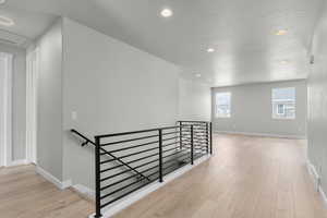 Hallway with light wood-type flooring and a textured ceiling