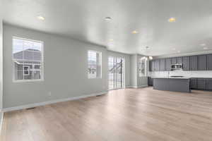 Unfurnished living room featuring a chandelier, light hardwood / wood-style floors, and a textured ceiling