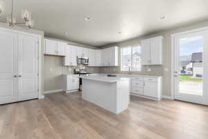 Kitchen featuring white cabinets, appliances with stainless steel finishes, and a wealth of natural light