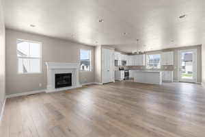 Unfurnished living room featuring a wealth of natural light, light hardwood / wood-style flooring, a chandelier, and a textured ceiling