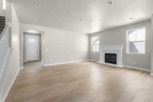 Unfurnished living room featuring light wood-type flooring and a textured ceiling